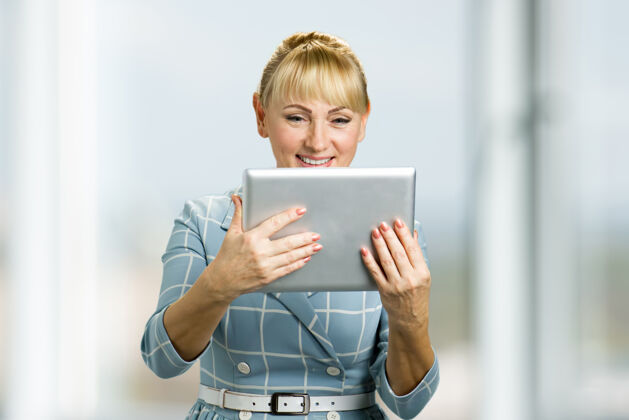 成熟微笑的成熟女人拿着pc平板电脑中年女人看着数字平板电脑微笑互联网女性员工