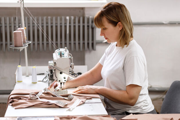 裁缝工厂里缝纫机后面的女裁缝线面料室内