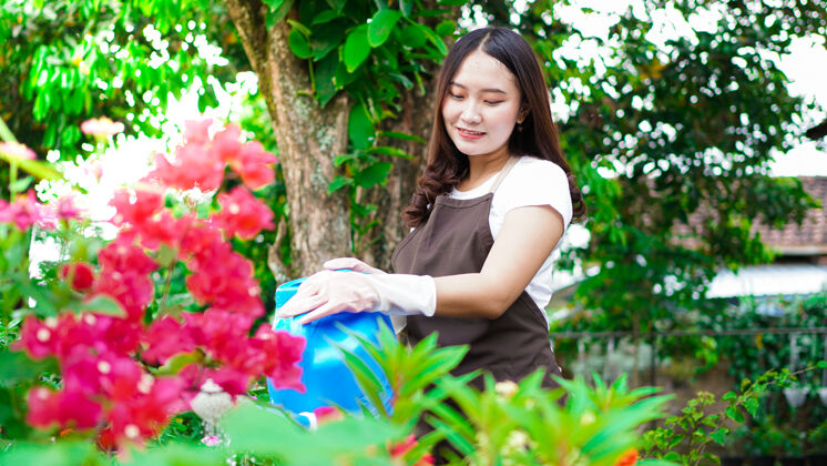 工具亚洲女人在家花园浇花园艺花花