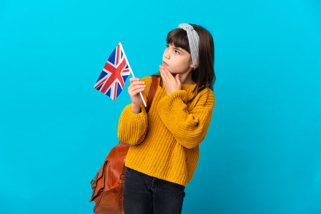 模型学习英语的小女孩孤零零地站在蓝色的墙上微笑着抬头看团结女孩眼睛