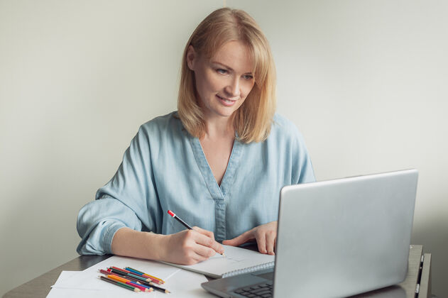 色彩一个金发女人在一个在线课程上画册电脑金发教育