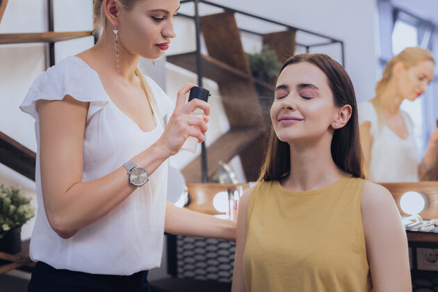 热热水金发迷人的化妆师用热水洒在她客户的脸上博客唇彩客户
