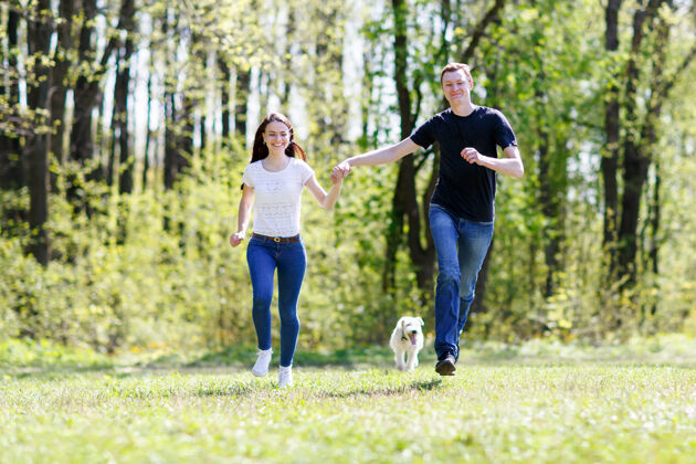 附近年轻幸福的一家人和狗在绿草地上奔跑关系男人微笑