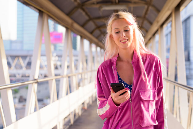 智能城市户外人行天桥上年轻漂亮的金发女郎的画像步行互联网女性
