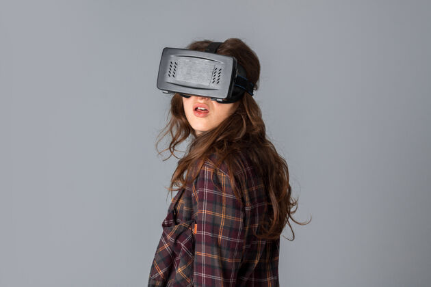 眼镜在灰色墙上的工作室里 戴着虚拟现实头盔的可爱女人的特写肖像屏幕Vr3d