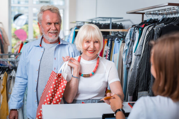 时尚最后的购买步骤积极的老年家庭传递一张信用卡给女售货员 同时对他们在购物店的购买感到满意时尚周末男性