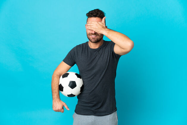 人足球运动员被隔离在蓝色背景下用手遮住眼睛不想看到什么乐趣运动盲人