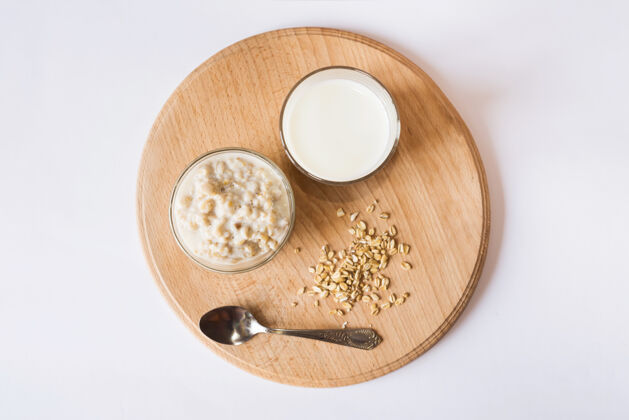 营养在白色表面的木板上放一碗麦片和一杯牛奶从上面看种子食物薄片