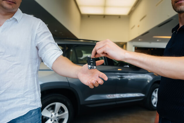 交易卖家把新车的钥匙递给一个年轻的家庭买一辆新车车辆微笑卖家