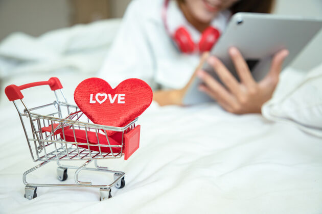 人亚洲美女用平板电脑在情人节买礼物和购物车用爱心短信肖像漂亮女人