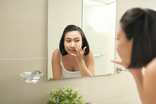 亚洲有魅力的女人在涂完面膜后在浴室里洗可爱皮肤手