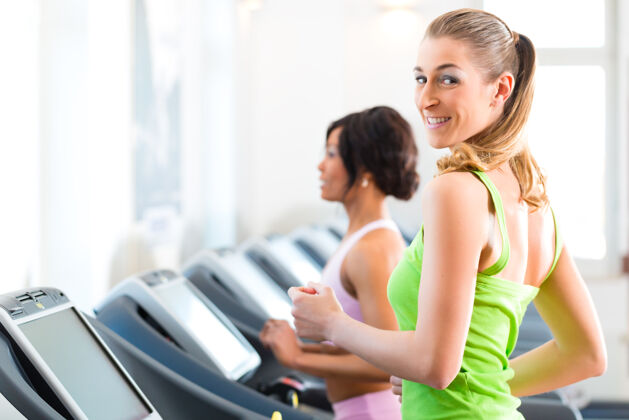 拉丁美洲人在健身房或健身俱乐部的跑步机上跑步-两个女人在锻炼以获得更多的健康年轻人俱乐部女人