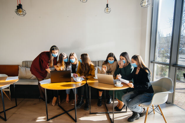 记录一群戴着面具的女孩坐在咖啡馆里用笔记本电脑工作教学生博客自由职业者女商人