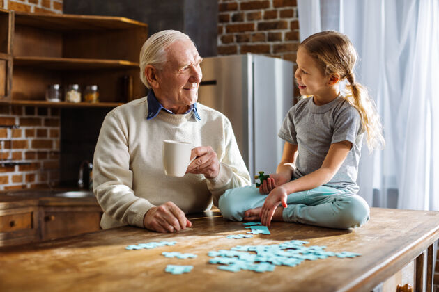 拼图在家休息时和孙女一起玩拼图游戏的快乐男人爷爷学校房子