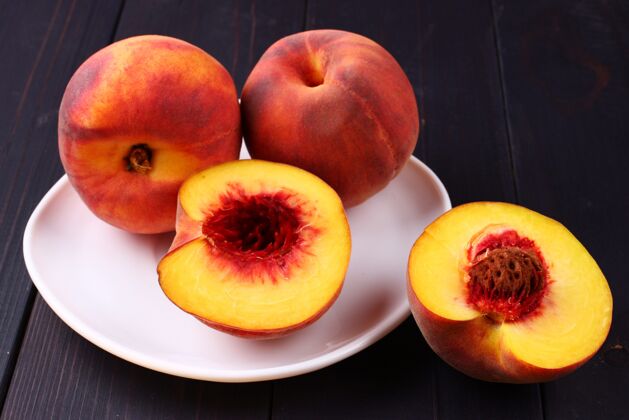甜点把桃子放在一个盘子里 放在一个深色的木头表面上切的饮食素食