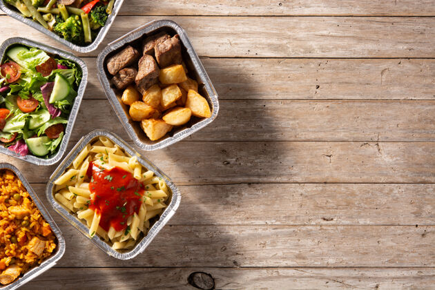 餐饮把健康食品放在木桌上的锡箔盒里带走膳食健康通心粉
