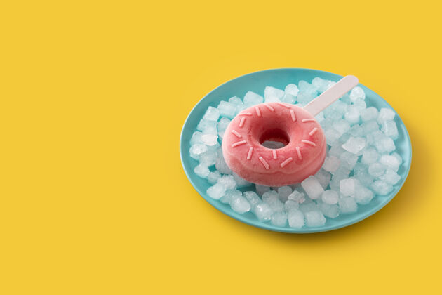 冷黄色桌子上的草莓甜甜圈冰棒和碎冰形状风味食品
