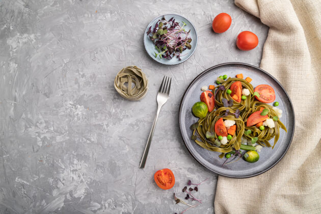 健康绿色菠菜面食 配番茄 豌豆和微绿芽菜 在灰色混凝土表面和亚麻织物上菠菜碗微绿色