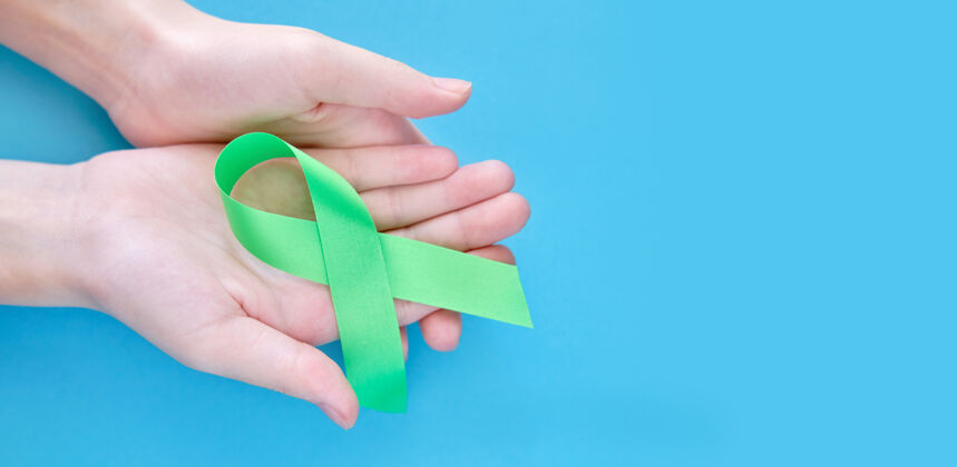 环境女人手上的绿色象征丝带覆盖在白色的表面上医学慈善移植