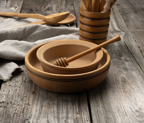厨房灰色桌子上的空圆木盘和勺子 蜂蜜棒圆木头圆