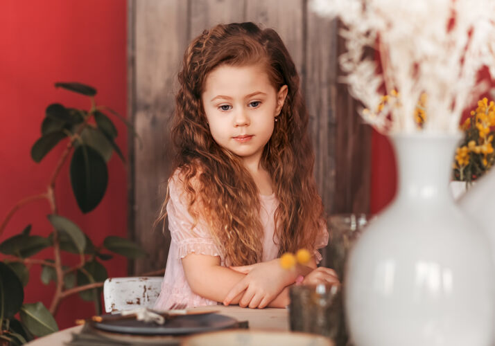 玻璃一个悲伤的小女孩坐在厨房里表.等待午餐盘子孩子坐着