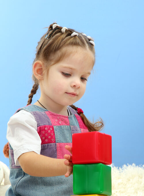 坐着可爱的小女孩在玩彩色积木 蓝色的房间玩耍休闲