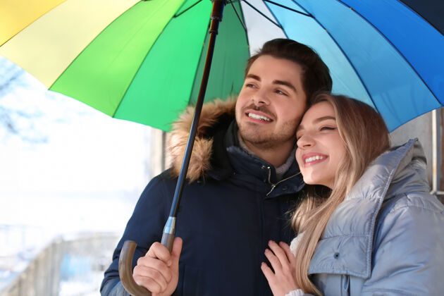 关系带着彩色雨伞的年轻浪漫情侣在户外情侣雨伞在一起