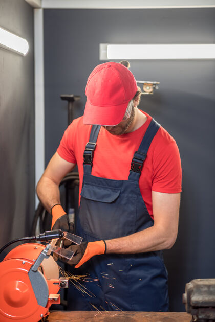 经验锐化工艺员戴着红帽 穿着T恤 在车间里修磨床细节汽车技工自营