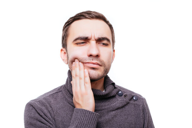 英国人有牙痛牙冠问题的年轻人的特写肖像 因为用手触摸嘴外的疼痛而要哭 隔离在白墙上雇员填充男孩