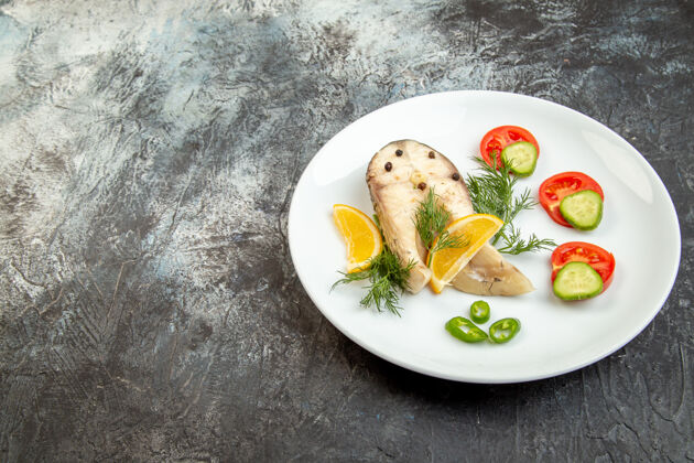 午餐灰色冰面左侧白色盘子上的生鱼和胡椒新鲜食物的正面视图 有自由空间胡椒粉一餐冰