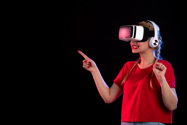 视觉在黑暗的视觉上 年轻女士戴着耳机玩虚拟现实的肖像耳机漂亮虚拟现实