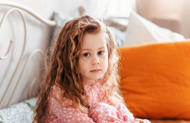 孩子一个可爱的卷发小女孩的肖像 看着镜头女孩喜怒无常沮丧