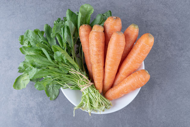 美味绿色蔬菜和胡萝卜放在碗里 放在大理石表面上生的风味农业