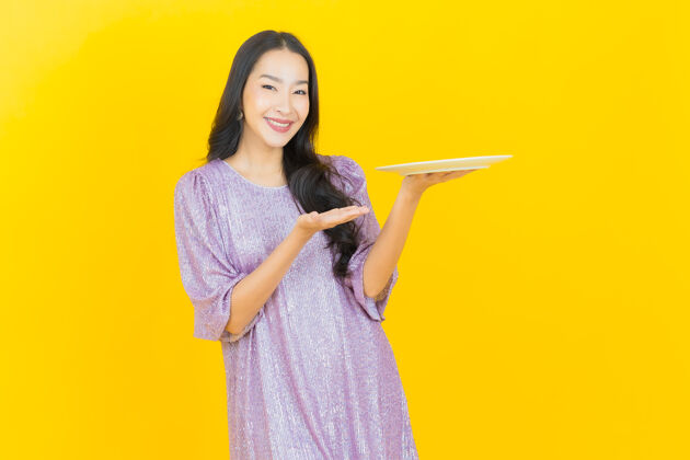 肖像年轻的亚洲女人拿着空盘子站立正面脸