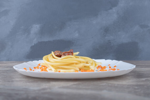 蛋白质把胡萝卜和意大利面磨碎 放在盘子里 放在大理石表面菜肴美味意大利面