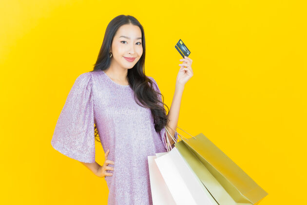 购物狂年轻的亚洲女人微笑着购物袋上的黄色买家女性女人