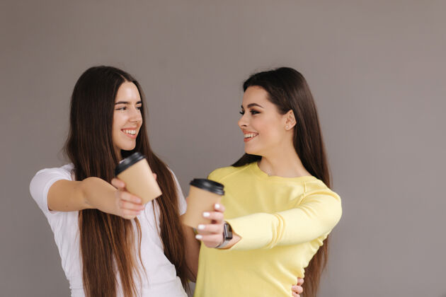 表情两个漂亮的女人端着一杯咖啡快乐手势人