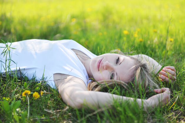 牛仔裤年轻漂亮的金发女郎正在公园的春天里休息放松金发散步