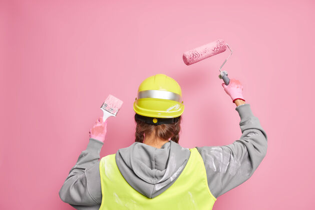 检查不要脸的专业建设者忙着重建建筑物 站在后面用设备粉刷墙壁 戴着防护安全帽 对着粉色的墙壁摆出统一的姿势重建手室内