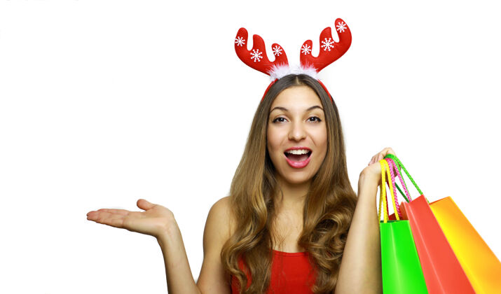 女人穿着驯鹿角和购物袋的快乐女人节日圣诞老人演示
