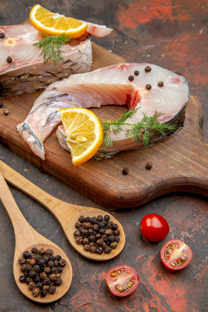 食物木砧板上的生鱼和胡椒的特写镜头混合色表面上的柠檬片西红柿健康板切片