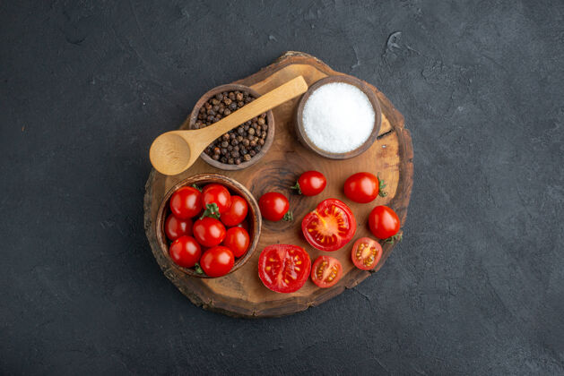 闪亮上图：黑色木板上的整个切好的新鲜西红柿和胡椒粉 有自由空间球整个水果