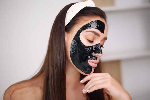 黑色一个戴着洁面黑面具的年轻漂亮女人的画像快乐皮肤护理粘土