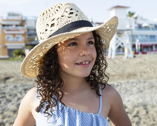 乐趣特写海滩上戴帽子的女孩海滩家庭假期