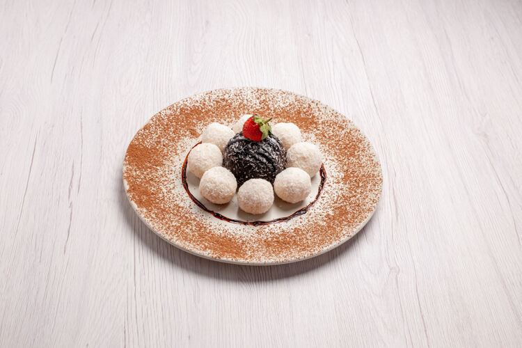 甜点正面是美味的椰子糖和巧克力蛋糕在白色空间容器糖草莓