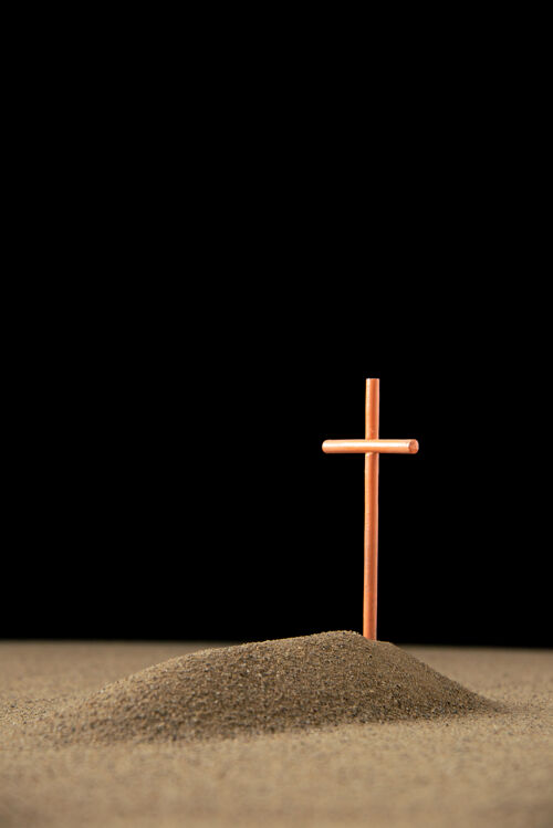 死亡黑暗中带十字架的小坟墓的正视图十字架沙子宗教