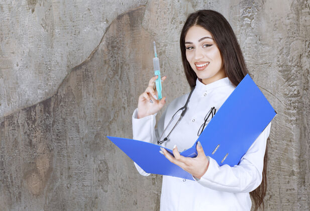护理面带微笑的年轻女医生拿着针剂和检查单看着前方年轻严重医生