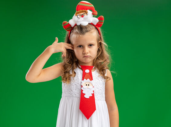 刮悲伤的小女孩戴着圣诞发箍 打着领带 耳朵被隔离在绿色的墙上圣诞节悲伤穿