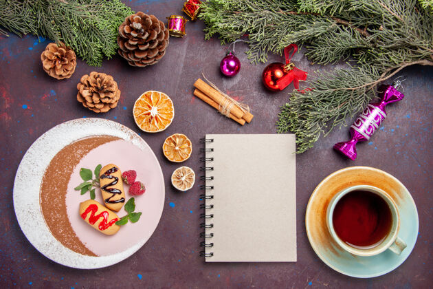热的俯瞰美味的甜饼干与一杯茶和圣诞树在黑暗的背景饼干甜饼干糖彩色蛋糕咖啡树顶部