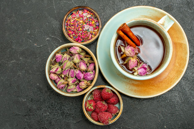早餐顶视图一杯茶 以花儿和覆盆子为深色背景 茶果饮花香香料覆盆子水果